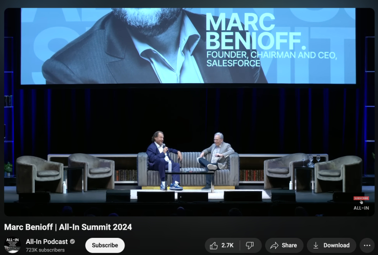 Marc Benioff, Founder, Chairman, and CEO of Salesforce, answering questions during a live discussion at the All-In Summit 2024 on a stage with a large backdrop featuring his name.