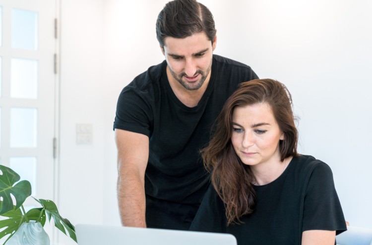 Two co-founders collaborating on creating a business plan while looking at a laptop.