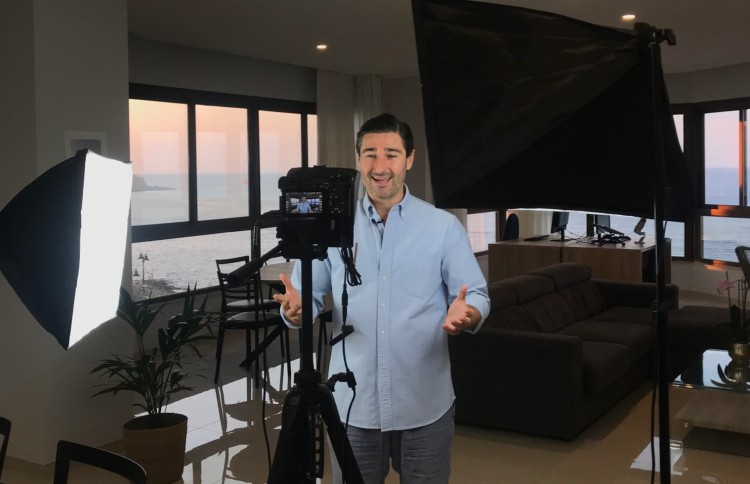 Man standing in front of camera and lights in a home studio setup, demonstrating how to start a video podcast.