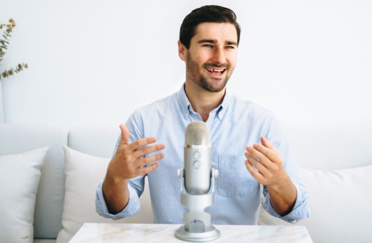 Liam Austin speaking while recording a podcast using a Blue Yeti microphone on a marble table