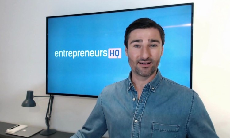 Liam Austin presenting in front of a screen with the Entrepreneurs HQ logo, showcasing a professional-quality podcast or webinar setup