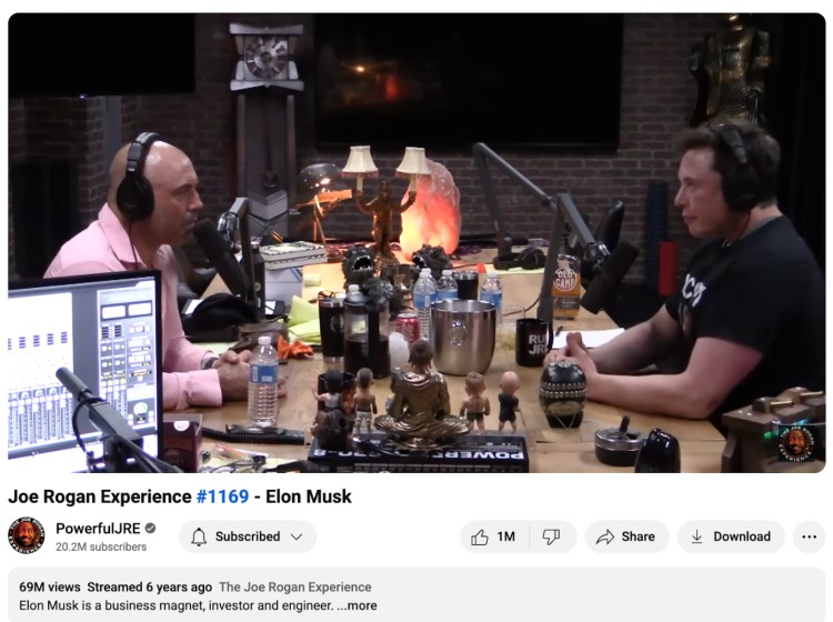 Podcast studio setup showing Joe Rogan interviewing Elon Musk, with microphones, headphones, and decorations visible in the image.