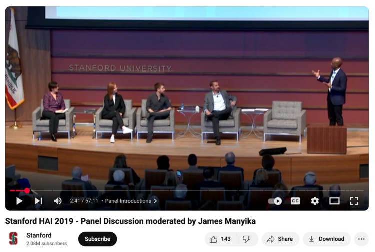 James Manyika leads the moderation of a panel discussion at Stanford HAI 2019 with four seated panelists on stage