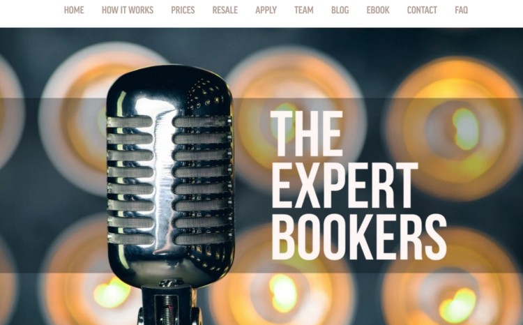 Close-up of a vintage microphone with glowing lights in the background and the text "The Expert Bookers," representing a podcast booking agency that helps experts get booked as a guest on shows.