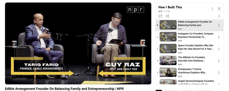 Interview setup from the How I Built This show with Guy Raz and Tariq Farid on stage, shown as a youtube video discussing entrepreneurship and business stories.