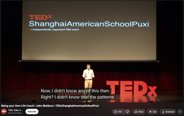 TEDx speaker demonstrating public speaking skills while presenting to an audience on stage